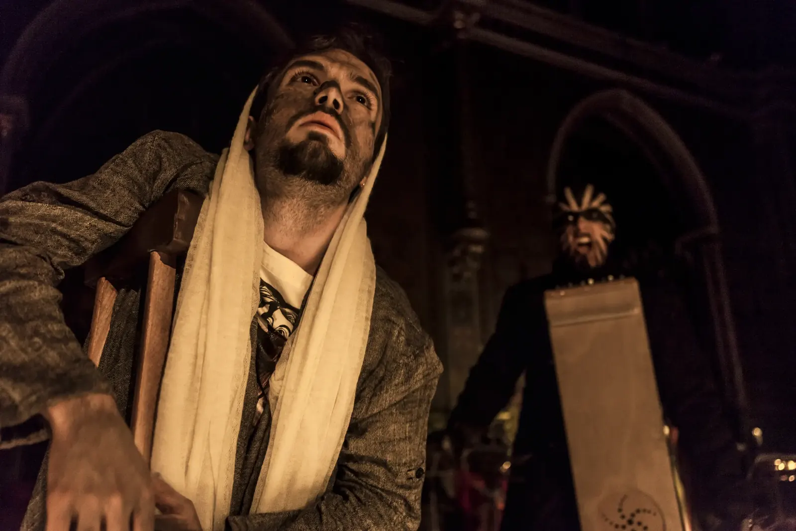 Juan, face darkened, in a pale shawl beside a masked figure