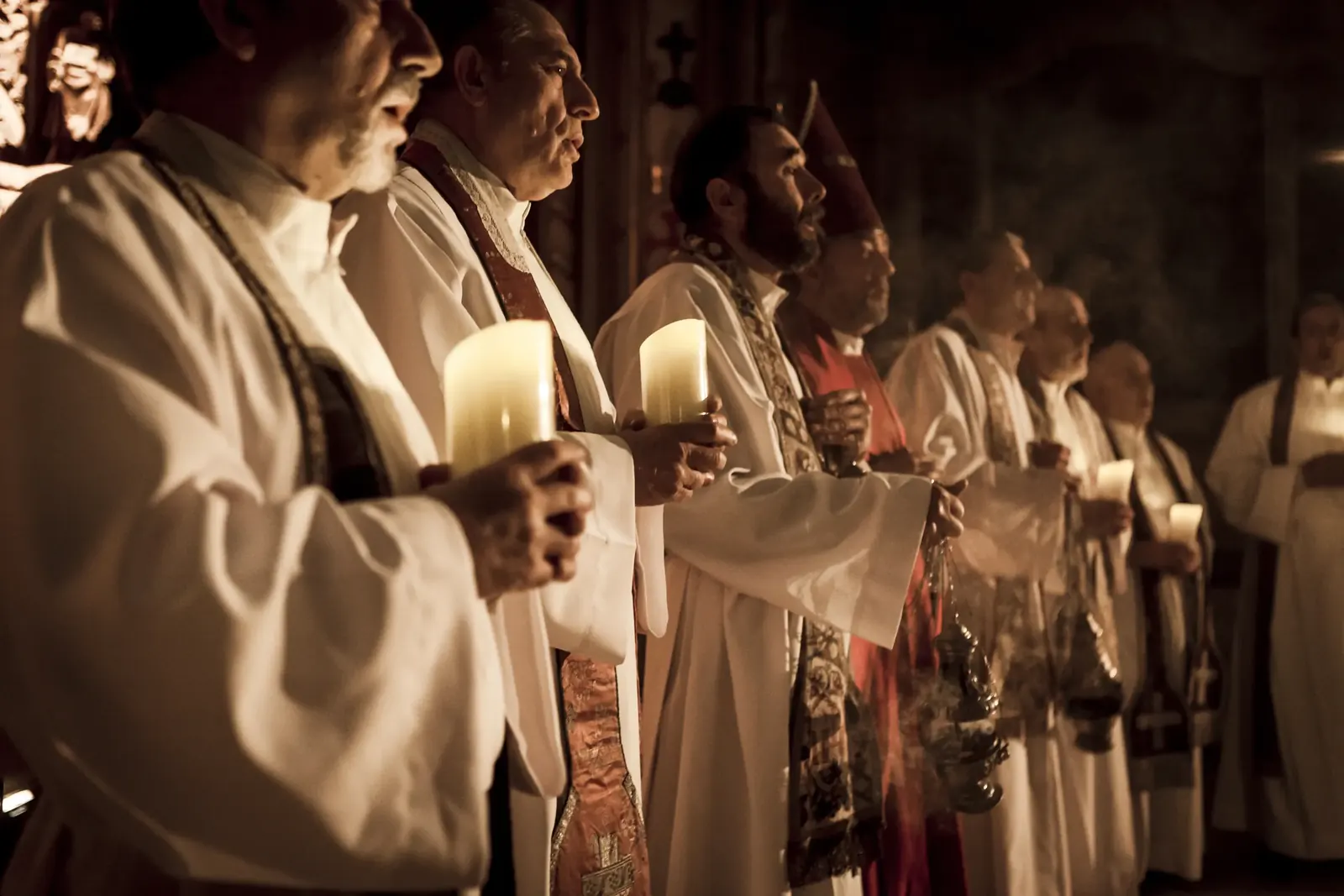 A line of robed clergy holding candles and censers